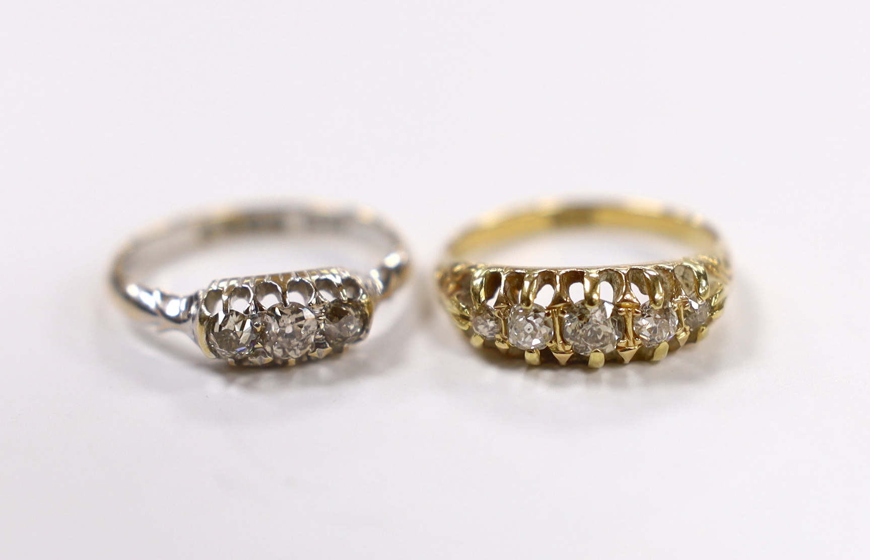 An early 20th century 18ct and claw set graduated old cut diamond half hoop ring, size N and an Edwardian 18ct white gold and three stone old cur diamond set ring, size N, gross weight 6.1 grams.